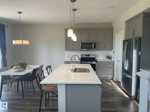 Kitchen featuring an island with an undermount sink, gray cabinetry, stainless steel appliances, and wood-finish flooring - 7939 Erasmus Crescent Nw, Edmonton, AB 