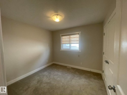 Carpeted flooring, neutral wall color, overhead flush-mount lighting, window with blinds, and white interior doors - 7939 Erasmus Crescent Nw, Edmonton, AB 