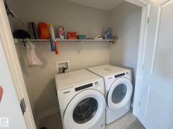 Dedicated laundry area with a white wire shelf, front-loading washer, and front-loading dryer - 