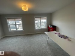 Plush carpeted flooring, two large windows, white trim, and an overhead light fixture - 