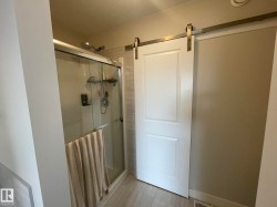 Walk-in shower with clear glass enclosure and sliding barn door - 