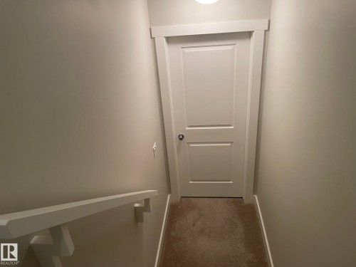 White paneled door with polished hardware, neutral wall paint, white trim, and carpeted flooring - 7939 Erasmus Crescent Nw, Edmonton, AB 
