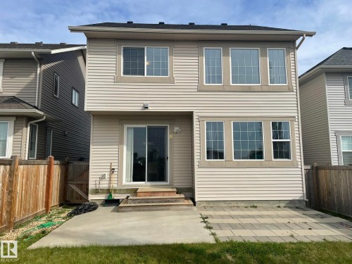 Rear exterior with light-colored siding, black shingle roof, and multiple large windows - 7939 Erasmus Crescent Nw, Edmonton, AB 
