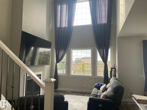 Two-story ceiling height with high transom windows, three ground-level windows, and a built-in fireplace - 7939 Erasmus Crescent Nw, Edmonton, AB 