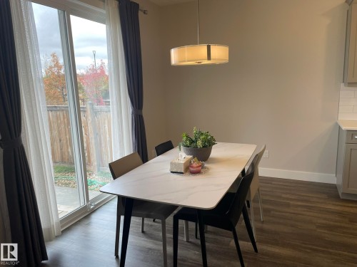 Sliding glass door, wood-finish flooring, and drum-style pendant light fixture - 7939 Erasmus Crescent Nw, Edmonton, AB 