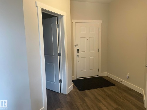 Entryway featuring wood-finish flooring, a white paneled door, and a modern door lock - 7939 Erasmus Crescent Nw, Edmonton, AB 