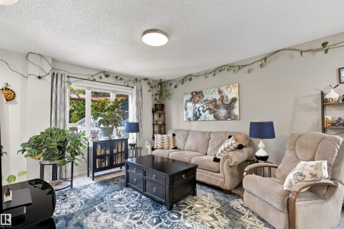 Bright living area with a large window, light-toned walls, and a ceiling-mounted flush light fixture - 38 Red Tail Way, St. Albert, AB 
