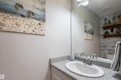 White oval sink with chrome faucet, light grey speckled countertop, white cabinetry - 