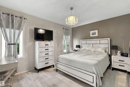 Light wood-finish flooring, a contemporary chandelier, multiple windows, and a two-tone wall finish - 38 Red Tail Way, St. Albert, AB 