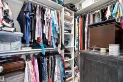 Custom closet storage system featuring multiple hanging rods, built-in shelving, and a central island with a wood-finish top - 