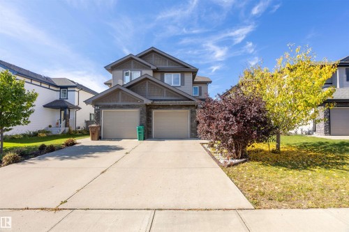 Two-story facade with stone and siding accents, dual garage doors, concrete driveway, and front landscaping - 38 Red Tail Way, St. Albert, AB 