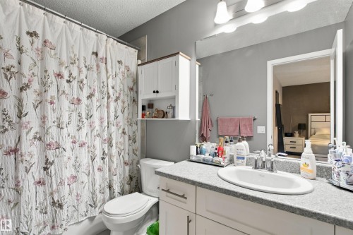 White vanity with brushed nickel hardware, integrated sink, and gray speckled countertop - 38 Red Tail Way, St. Albert, AB 