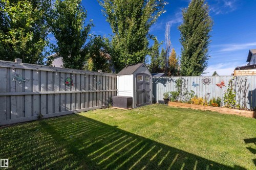 Enclosed backyard featuring a privacy fence, a storage shed, and a raised garden bed - 38 Red Tail Way, St. Albert, AB 
