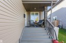 Front porch featuring a stone-clad support column and wood railings - 38 Red Tail Way, St. Albert, AB 