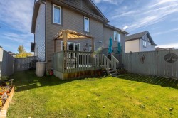 Expansive backyard featuring a manicured lawn, a wooden deck with railing, and a privacy fence - 