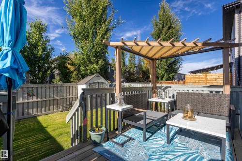 Wood deck with a pergola featuring a retractable fabric cover, wood privacy fence, and a storage shed - 38 Red Tail Way, St. Albert, AB 