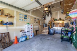 Spacious garage featuring polished concrete flooring, wall-mounted storage systems, overhead bike racks, and abundant shelving for organization - 