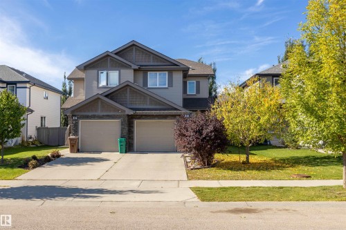 Two-story duplex featuring a dual garage, stone accents, and composite siding - 38 Red Tail Way, St. Albert, AB 
