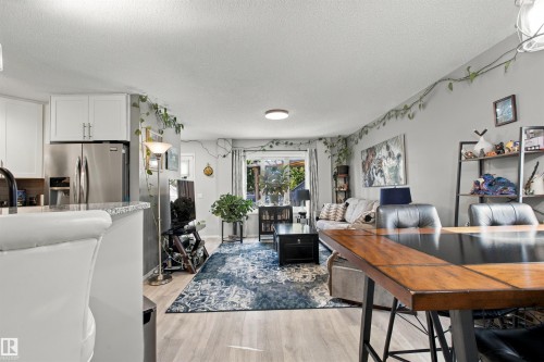 Light wood-finish flooring throughout, complemented by a kitchen featuring white cabinetry and stainless steel appliances - 38 Red Tail Way, St. Albert, AB 
