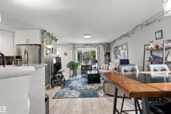 Light wood-finish flooring throughout, complemented by a kitchen featuring white cabinetry and stainless steel appliances - 