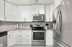 White shaker-style cabinetry with brushed nickel hardware, stainless steel appliances, speckled countertops, and a subway tile backsplash - 