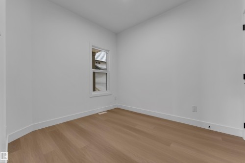 Bright interior with wood-finish flooring and a single white-framed window - 794 Bank Drive, Leduc, AB 