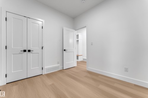 Light wood-finish flooring, white walls, white trim, and white paneled doors with matte black hardware - 794 Bank Drive, Leduc, AB 