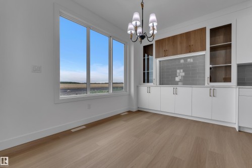 Wide plank wood-finish flooring, large multi-pane windows, built-in cabinetry with white lower doors, wood-finish upper cabinets, and glass-front upper cabinets - 794 Bank Drive, Leduc, AB 
