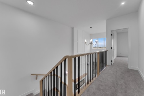 Upper level hallway featuring recessed lighting, a chandelier, wood and metal banister, and carpeted flooring - 794 Bank Drive, Leduc, AB 