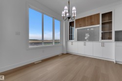 Wide plank wood-finish flooring, large multi-pane windows, built-in cabinetry with white lower doors, wood-finish upper cabinets, and glass-front upper cabinets - 