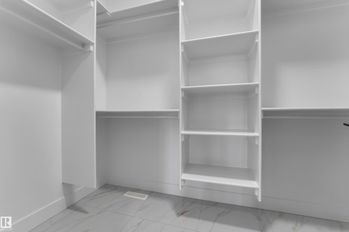 Integrated closet system with multiple shelving units, hanging rods, and light-toned tile flooring - 794 Bank Drive, Leduc, AB 