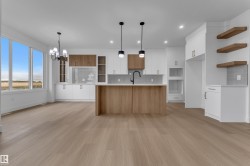 Bright kitchen featuring a central island with an undermount sink, pendant lighting, built-in appliances, and wood-finish flooring - 
