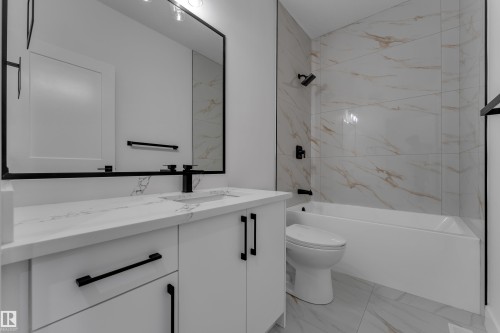 White vanity with integrated sink, black fixtures, framed mirror, and tiled shower/tub combination - 794 Bank Drive, Leduc, AB 