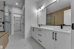 Bathroom featuring a dual vanity with white cabinetry, integrated sinks, and black fixtures - 
