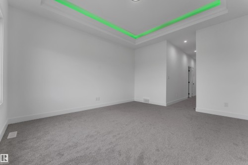 Recessed tray ceiling with accent lighting, neutral carpeting, and white painted walls - 794 Bank Drive, Leduc, AB 