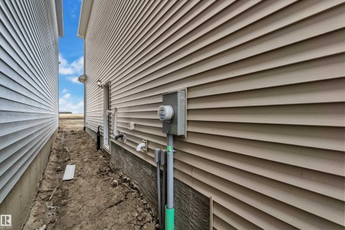 Tan horizontal vinyl siding with a single outdoor wall light - 794 Bank Drive, Leduc, AB 