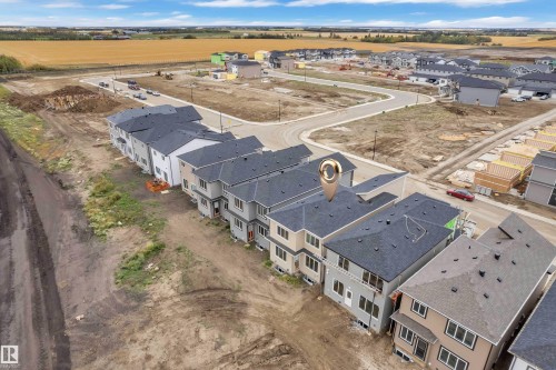 New construction development featuring multiple residential units, paved roadways, and a surrounding open landscape - 794 Bank Drive, Leduc, AB 