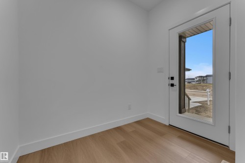 Wood-finish flooring, white walls, and a full-light entry door with matte black hardware - 794 Bank Drive, Leduc, AB 