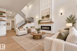 Vaulted ceiling, linear electric fireplace with stone surround, wood-finish mantel, wood-finish flooring, and open-tread staircase with black metal balusters - 
