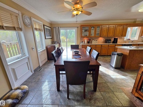 Open-concept living space featuring wood-finish cabinetry, tile flooring, multiple windows, and a sliding glass door - 9131 Township Road 554, Rural St. Paul County, AB 