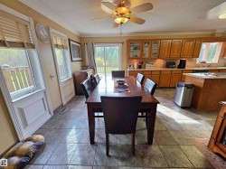 Open-concept living space featuring wood-finish cabinetry, tile flooring, multiple windows, and a sliding glass door - 