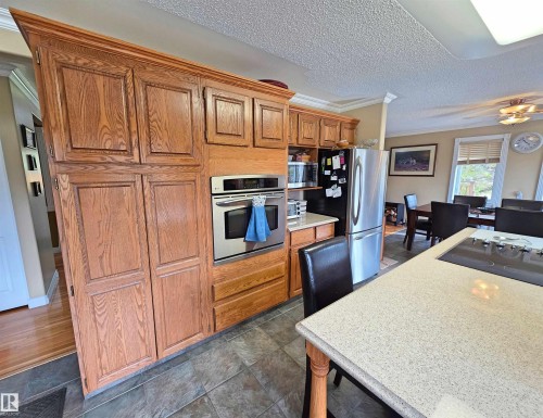 Kitchen featuring wood cabinetry, stainless steel double oven, stainless steel refrigerator, and quartz countertops - 9131 Township Road 554, Rural St. Paul County, AB 