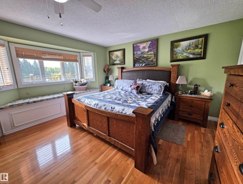 Bay window with integrated window seat, wood-finish flooring, ceiling fan, and painted walls - 9131 Township Road 554, Rural St. Paul County, AB 