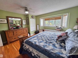 Hardwood flooring, ceiling fan with integrated lighting, bay window with integrated window seat, white bi-fold closet doors, and wood-finish window blinds - 
