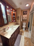 Rich wood-finish vanity with an integrated sink and light-toned countertop with a walk in shower - 