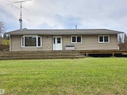 Ranch-style exterior with neutral siding, a bay window, and a full-width wooden deck - 