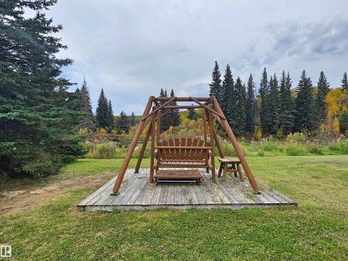 Expansive lawn area featuring a wooden swing set on a raised deck - 9131 Township Road 554, Rural St. Paul County, AB 