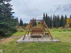 Expansive lawn area featuring a wooden swing set on a raised deck - 