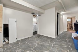 Spacious basement room with patterned tile flooring, white finished walls, and multiple doorways providing access to adjoining spaces - 