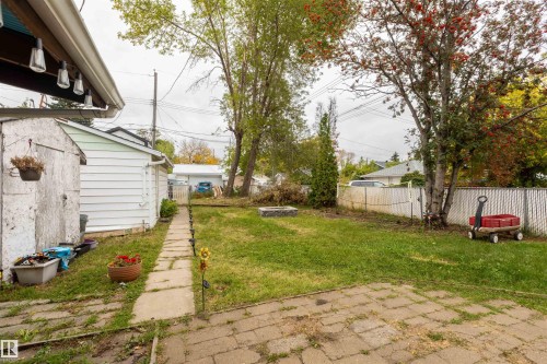 Spacious backyard with mature tree-lined perimeter, level lawn, and concrete pathway - 12707 73 Street Nw, Edmonton, AB 